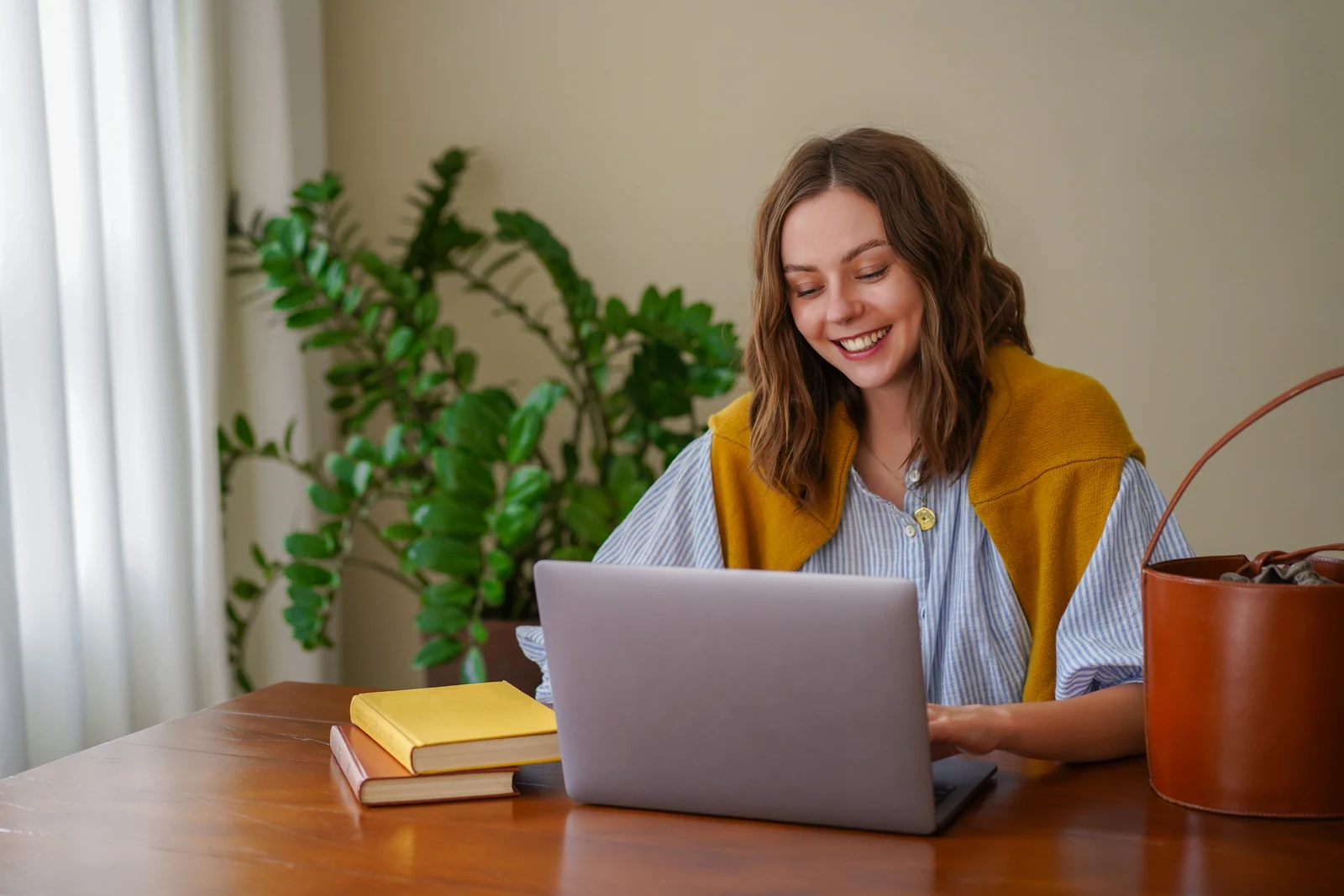 Smiling student working on a laptop at home after handing over an assignment
