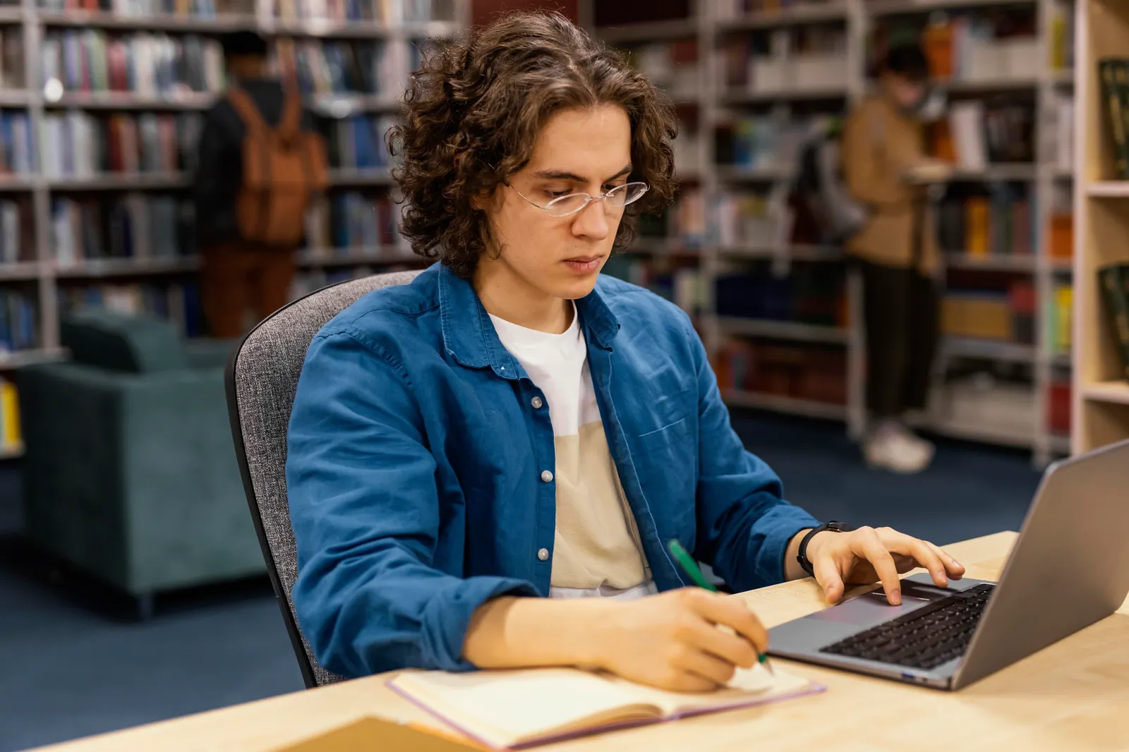 University student typing on a laptop in a library to buy an assignment online