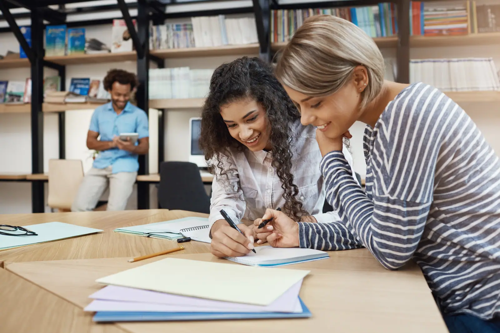Two students reviewing a custom assignment together at a library table